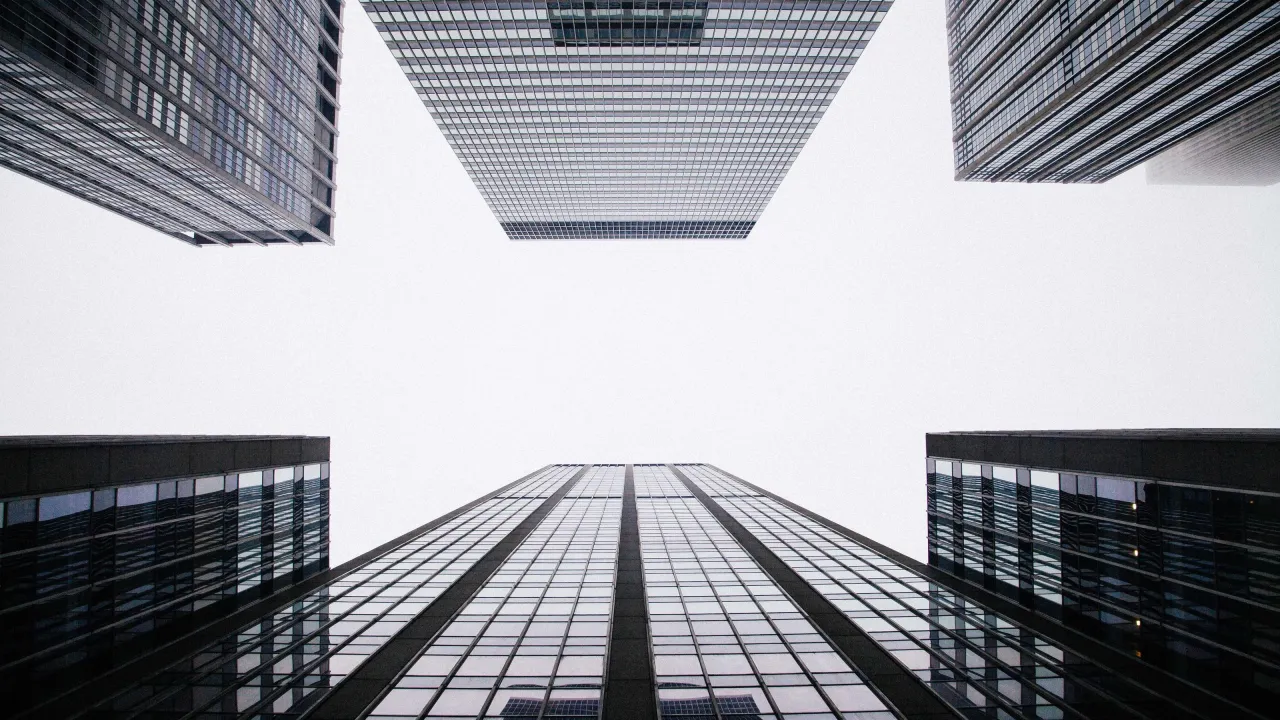 Glass skyscrapers seen from below against a bright sky