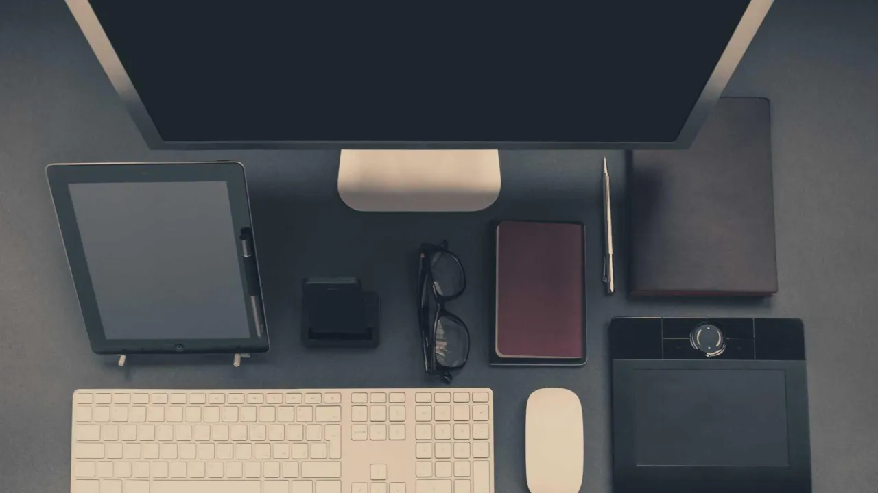 Dark desk setup with monitor, tablet and keyboard neatly arranged